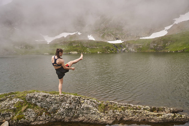 Kickboxer girl training by a lake in the mountains - Valokuva, kuva