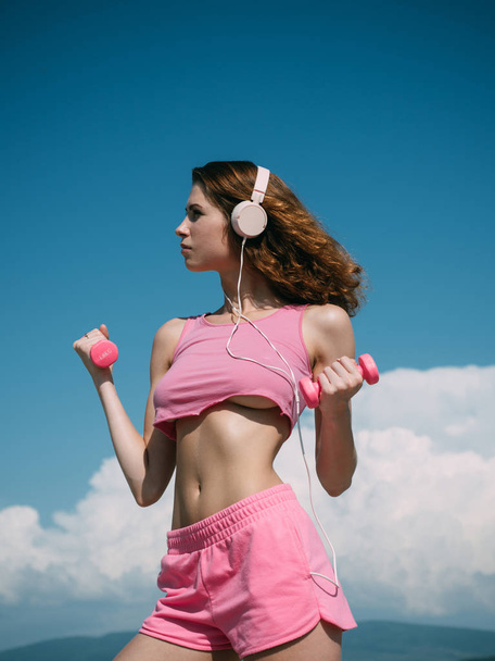 dumbbell lifting. sport and fitness. healthy lifestyle. dieting. freedom. girl with fit belly. sporty girl training outdoor. perfect body muscle. summer activity. barbell equipment. music for gym - Φωτογραφία, εικόνα