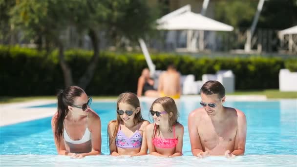 Familia feliz de cuatro en la piscina al aire libre - Imágenes, Vídeo
