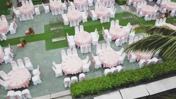 Drone flying over wedding dinner decoration, or marriage anniversary, in the garden outdoor, catering setting chairs and tables, aerial view. Tropical decor style atmosphere. - Footage, Video