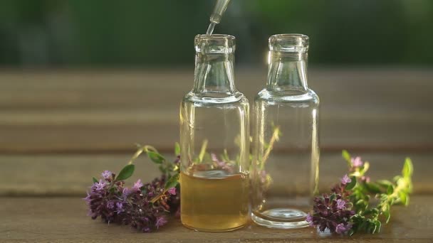 Ätherisches Thymianöl in schöner Flasche auf dem Tisch - Filmmaterial, Video