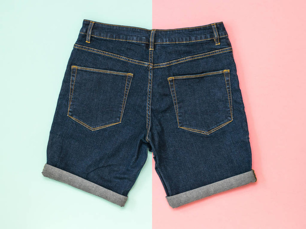 Pantaloncini in denim blu su fondo rosa e blu. Abbigliamento unisex alla moda
. - Foto, immagini