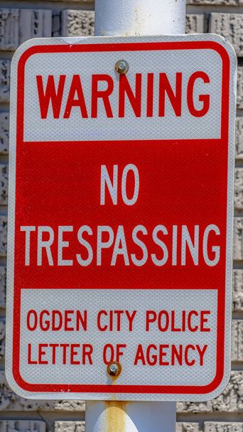Verticale hoog frame waarschuwing geen trespassing teken tegen een metalen paal en ruwe bakstenen muur - Foto, afbeelding