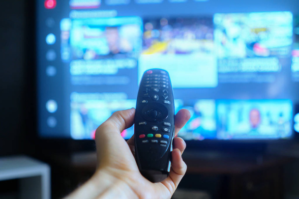 hand houden van een tv-afstandsbediening, swithing media chanels schermen - Foto, afbeelding