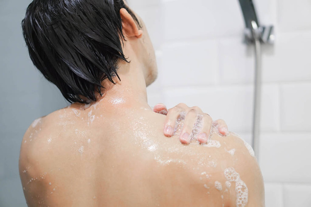 Primer plano guapo asiático hombre tomando una ducha en el baño, enfoque selectivo
 - Foto, imagen