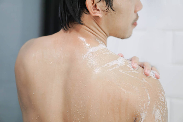 Close-up knappe Aziatische man het nemen van een douche in de badkamer, selectieve focus - Foto, afbeelding