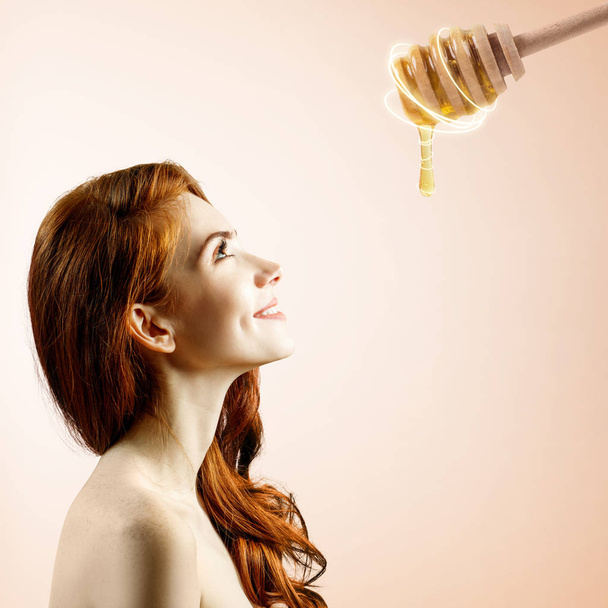 Jovem mulher olha para colher com mel e se preparar para a máscara
. - Foto, Imagem
