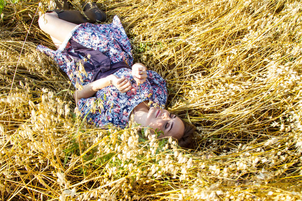 女の子は熟した耳の間の野原に横たわっている - 写真・画像