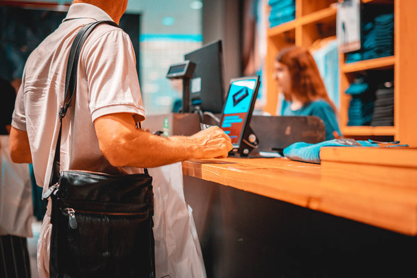 felnőtt fogyasztó fizet hitelkártyával a boltban, kezében egy pénztárcát - Fotó, kép