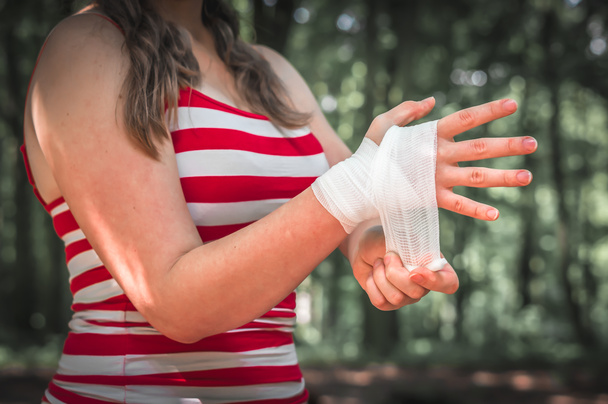 Жінка наносить пов'язку на руку після травми
 - Фото, зображення