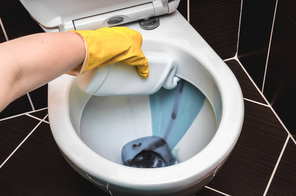 Woman is cleaning toilet bowl using detergent - Foto, Bild