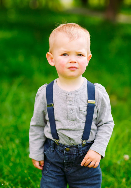 Little boy in denim overalls in the park. - Fotó, kép