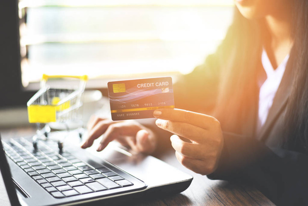 Frau hält Kreditkarte in der Hand und benutzt Laptop für Online-Shop - Foto, Bild