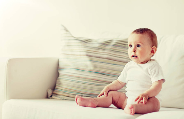 happy baby boy or girl sitting on sofa at home - Φωτογραφία, εικόνα