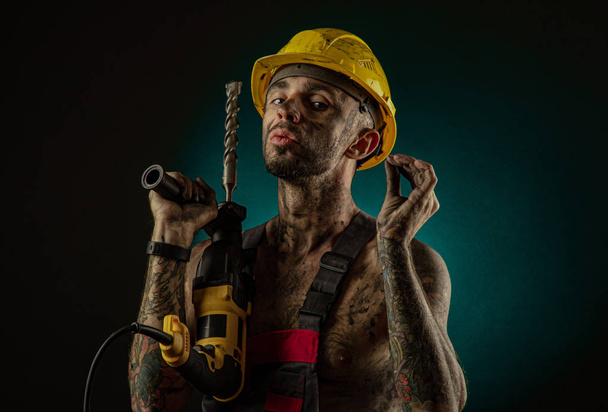 Un hombre minero con la ropa de un trabajador y un casco, sucio, en hollín, con un cuerpo desnudo, muecas a la cámara
 - Foto, imagen