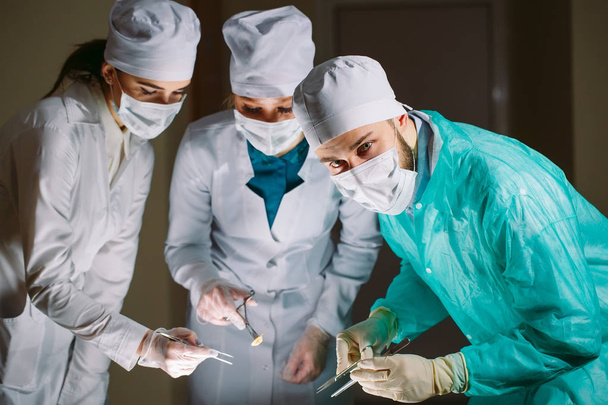 Il chirurgo e i suoi assistenti fanno un'operazione.
. - Foto, immagini