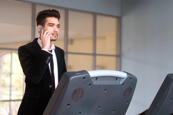 Businessman in white shirt and suit with phone on the treadmill  - Zdjęcie, obraz