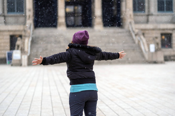 Rückseite einer asiatischen jungen Frau, die im Schnee spielt, wenn gerade Schnee gefallen ist, Reise- und Aufregerkonzept, Wollmütze mit Schart und Mantel für die Wintersaison - Foto, Bild