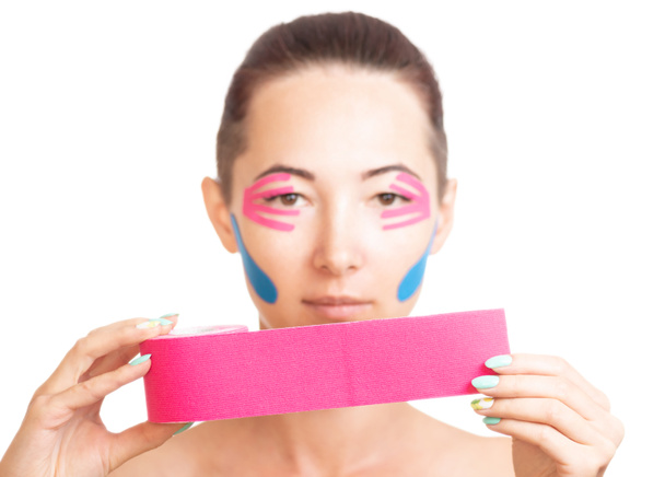 Woman with facelift taping holding roll of kinesiology tape. - Fotoğraf, Görsel