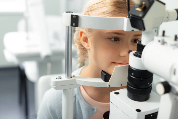 Girl looking into special glasses while having eye sight consultation - Valokuva, kuva
