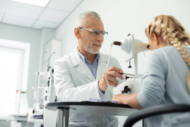 Grey-haired aged eye doctor wearing glasses consulting girl - Fotoğraf, Görsel
