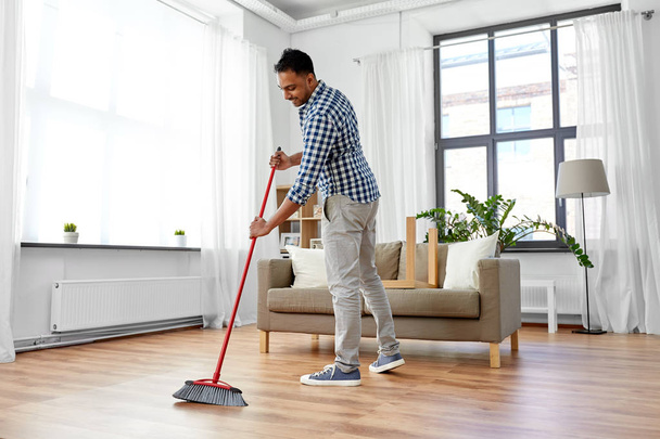 man with broom cleaning floor at home - Фото, зображення