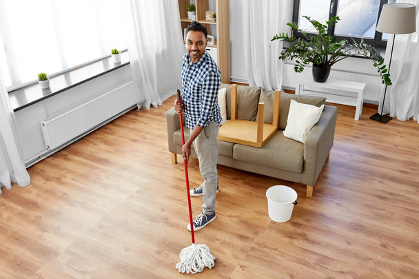 indian man with mop and bucket cleaning at home - Valokuva, kuva
