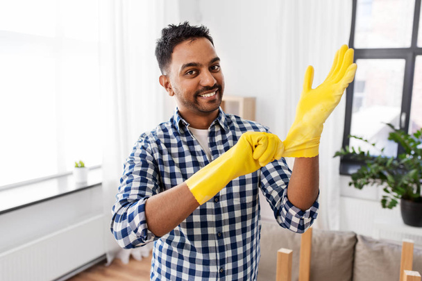 indian man putting protective rubber gloves on - Foto, afbeelding