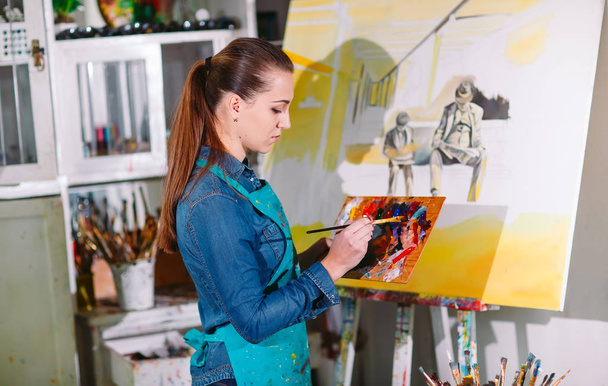 Beautiful Girl in a Painting Studio draws a picture. - Foto, Imagen