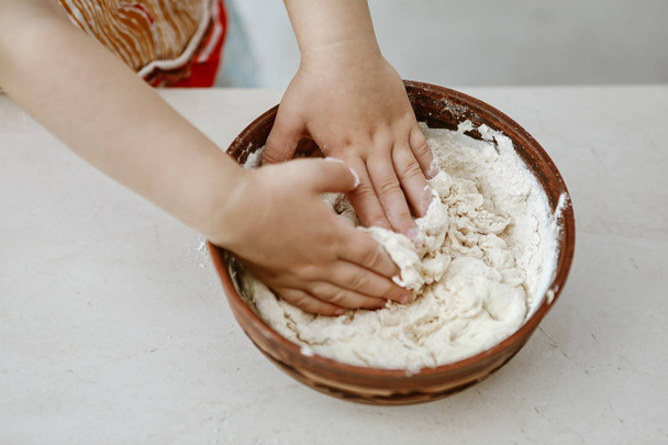 baby hands knead the dough in a pizza plate - Foto, Imagen