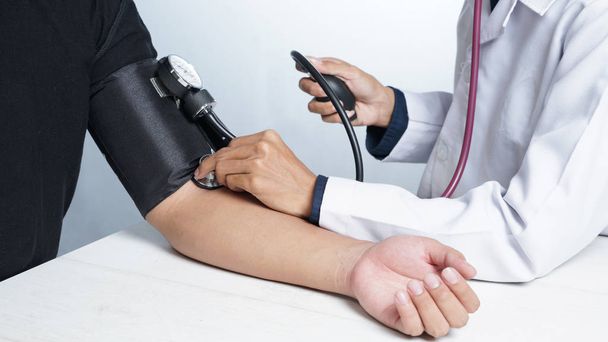 テーブルで患者の血圧をチェックする男性医師のトリミング画像 - 写真・画像