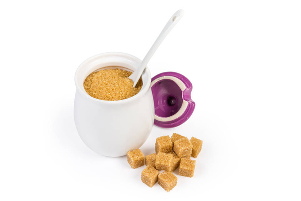 Brown sugar in sugar-bowl and brown sugar cubes beside - Photo, Image
