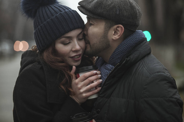 Rakastava pari, kahvin juominen, ulkona, kaupunkien hämärä aika
 - Valokuva, kuva