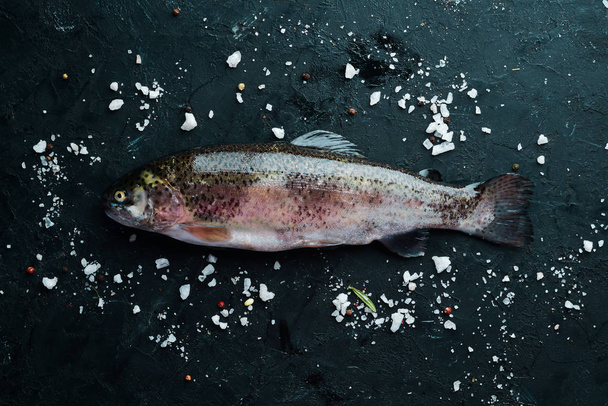 Raw fish trout on a black background. Top view. Free space for your text. - Фото, изображение