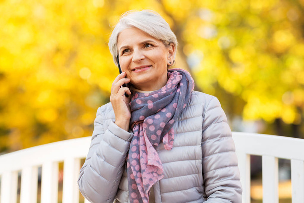 senior woman calling on smartphone at autumn park - Foto, immagini