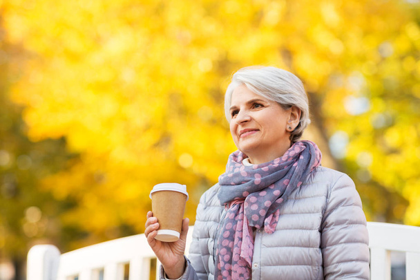 senior woman drinking coffee in autumn park - Valokuva, kuva