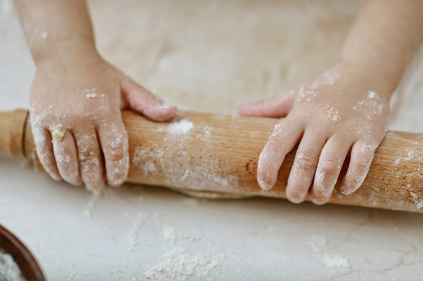 baby hands rolling dough with a rolling pin - Photo, Image