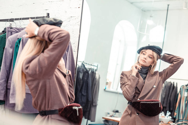 Blonde woman with long straight hair trying on new hat - 写真・画像