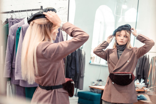 Fashion blogger looking into mirror while trying nice hat - Fotó, kép