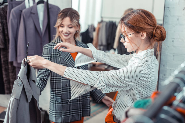 Shopping assistant in glasses showing client nice coat - Foto, Imagem