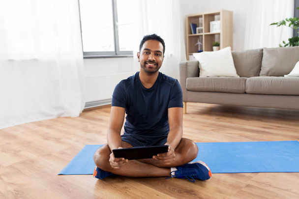 indian man with tablet pc and exercise mat at home - Foto, immagini