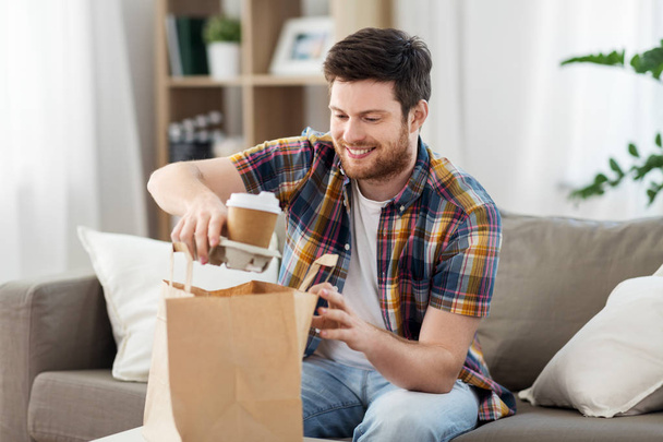 smiling man unpacking takeaway food at home - Photo, Image