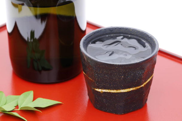 Bottle of Japanese shochu and ceramic bowl on wooden tray, on white background  - Photo, Image