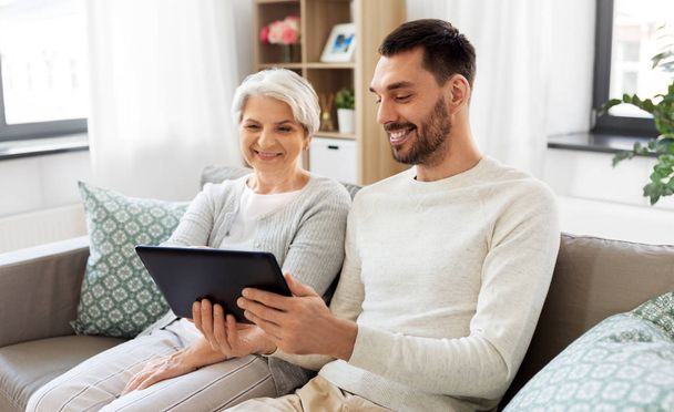 old mother and adult son with tablet pc at home - Foto, imagen