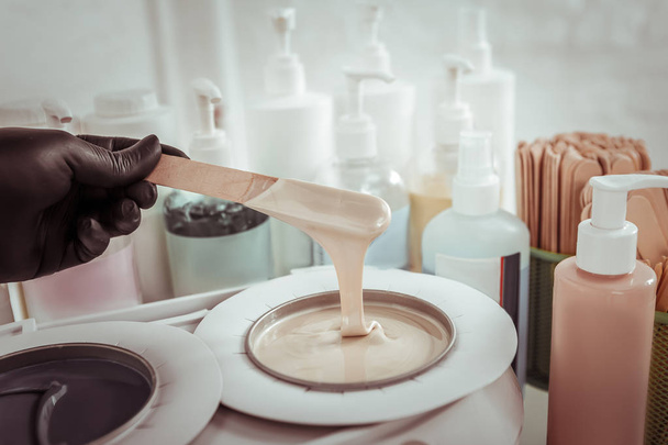 Beauty salon worker taking melted wax with wooden spatula - Fotoğraf, Görsel
