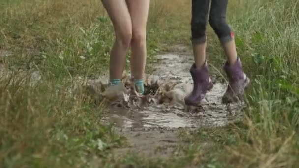 Legs of two children girls in boots jumping in rainy little puddle - Video, Çekim