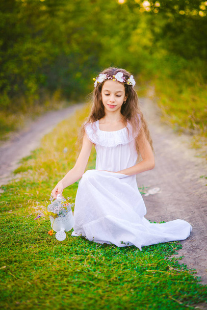 A sweet little girl  in white dress stands on the river in a summer  at sunset. - 写真・画像