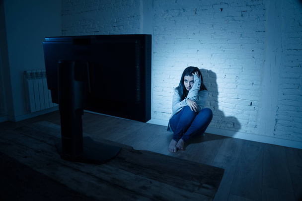 Dramatic portrait of sad scared young woman on the ground staring a computer suffering cyberbullying and harassment. Being online abused by stalker feeling desperate. Dangers of internet concept. - Fotó, kép