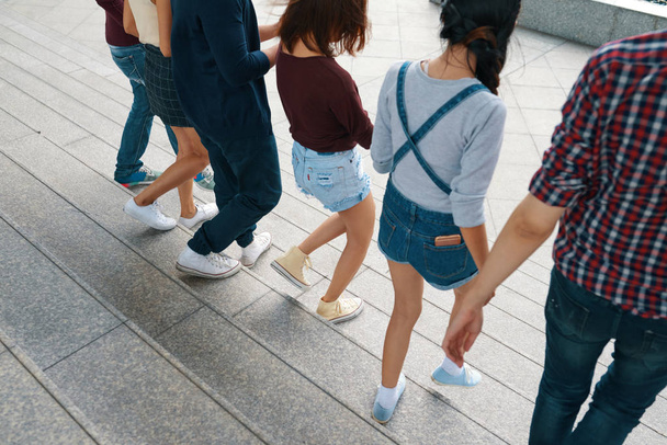 Обрезанный образ молодых людей, держащихся за руки, когда они выходят на улицу
 - Фото, изображение