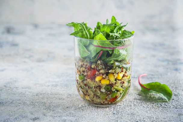 quinoa with vegetables in a glass cup with lettuce leaves, healthy eating concept, dietary vegetarian dish. Close-up, copy space, gray background. - Φωτογραφία, εικόνα